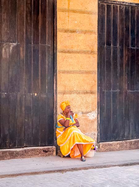 mujer cubana con un vestido amarillo fumando un cigarro en La Habana