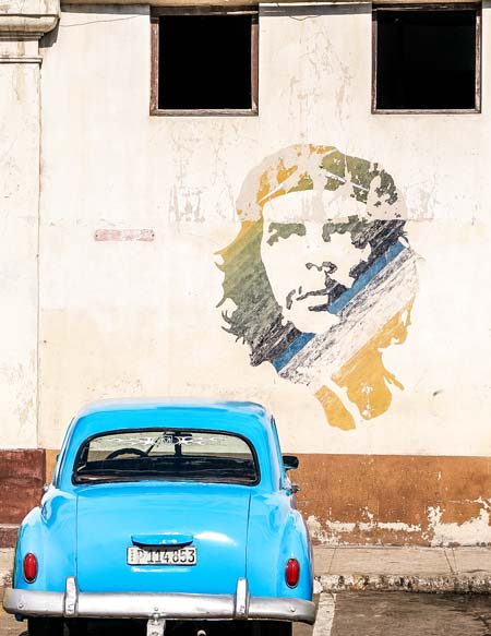 coche viejo azul y el retrato del Che Guevara en La Habana