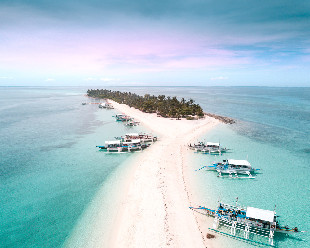 una vista de la isla de arena blanca y palmeras, barcos filipinos que necesita agregar a sus lugares de lista de cubos de ensueño