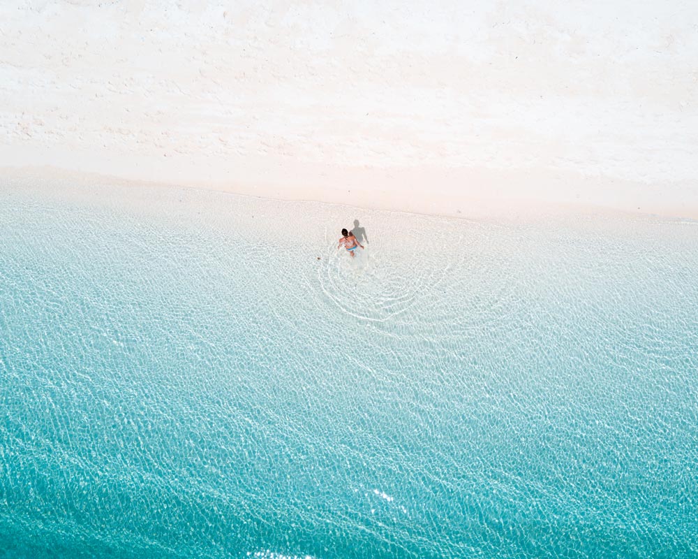 una chica corriendo en el agua azul y la arena blanca en la isla de Kalanggaman que necesita estar en su itinerario de Cebú