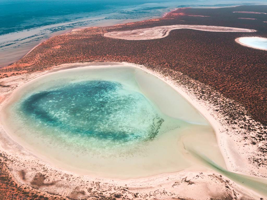 una vista aérea sobre lagunas azules, arena roja, parte del Parque Nacional Francios que es una de las mejores cosas para hacer en Shark Bay