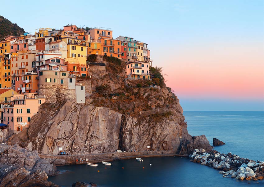 una vista sobre el cielo rosa, casas coloridas en el acantilado en Cinque Terre en Italia, uno de los lugares más bonitos de la lista de cubos en el mundo