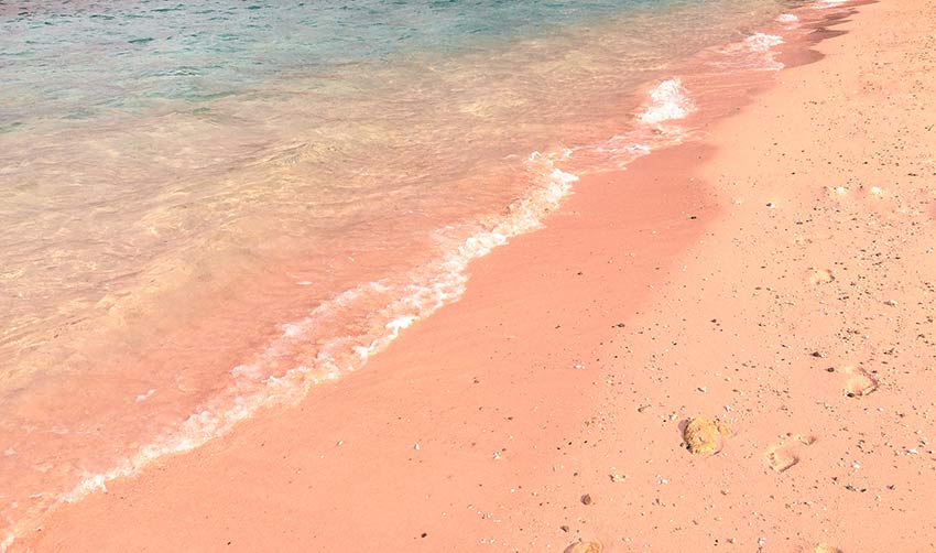 playa de arena rosa y agua azul