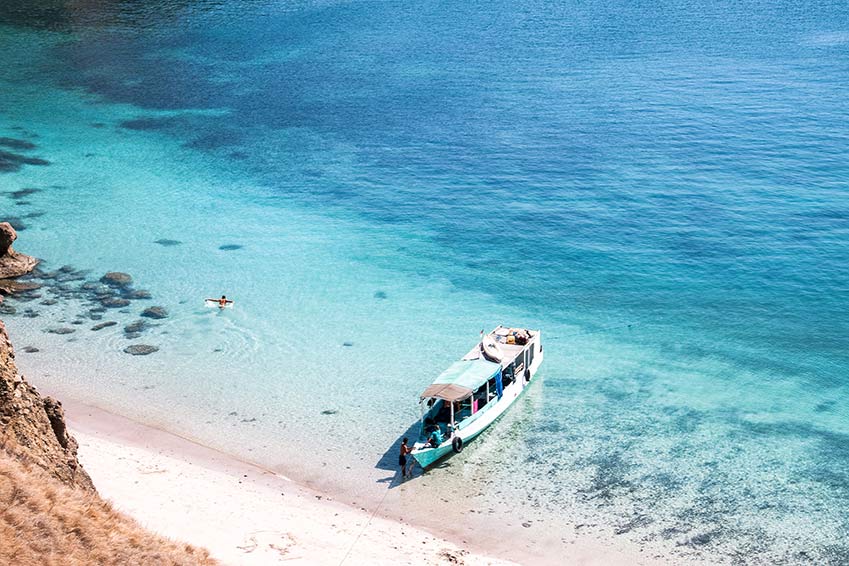 una vista sobre el agua turquesa con un barco en la isla de Padar