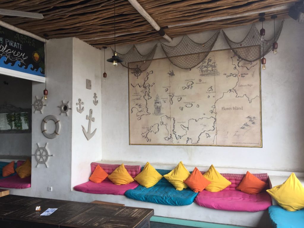 una mesa y un banco con almohadas coloful y un mapa encima en una pared