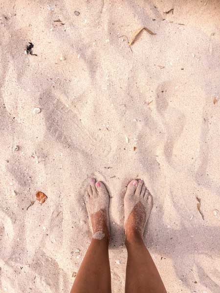 vista en los pies de pie en la playa de arena rosa en Labuan Bajo, Indonesia