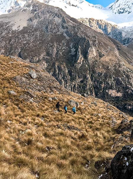 tres personas caminando entre las montañas en los Andes peruanos