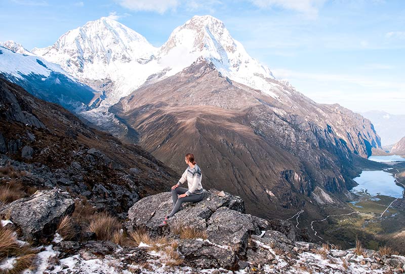 una mujer sentada en la roca frente a la, Huarascan, montañas nevadas y lagos